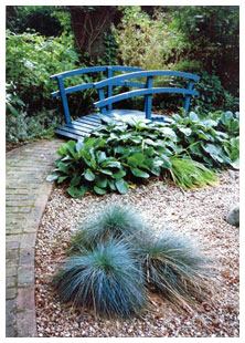 A bridge with lush planting gives the effect of water.  The gravel garden contains striking architectural plants and is low maintenance.  This garden design is in St Albans, Hertfordshire.