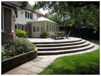A large raised patio designed to give easy access from kitchen, dining room and conservatory and plenty of room for outdoor dining and leisure activities.  Sweeping steps provide easy access to the lawn.  A rear garden design in Hertfordshire.